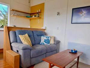 a living room with a blue couch and a table at Redshed Studio Mangawhai in Mangawhai