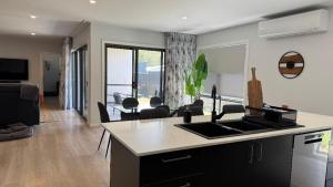 eine Küche und ein Wohnzimmer mit Spüle und Herd in der Unterkunft Azure Abode in Broulee
