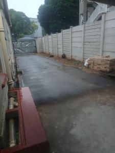 an empty driveway with a fence and a building at Clark lodge at 272 in Durban