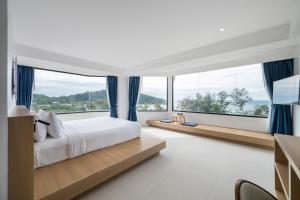 a bedroom with a large bed and large windows at Kokotel Rayong Beachfront in Ban Pak Khlong Phe