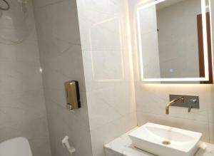 Un baño blanco con lavabo y espejo. en Hotel Lime Pride Park Near By IGI Airport Delhi, en Nueva Delhi