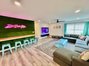 Sleeps 22, 2min Walk To The Beach, Heated PoolSpa في جنوب جزيرة بادري: غرفة معيشة مع أريكة وبار مع كراسي