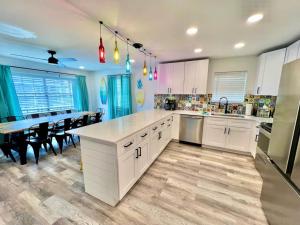 Sleeps 22, 2min Walk To The Beach, Heated PoolSpa في جنوب جزيرة بادري: مطبخ كبير مع دواليب بيضاء وطاولة طعام