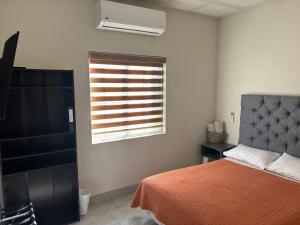 Un dormitorio con una cama y una ventana con persiana. en Casa Nogales, en Ciudad Juárez