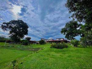 a green field with houses and trees in the background at Hotel Campestre Jardín del Café Quindío in Armenia