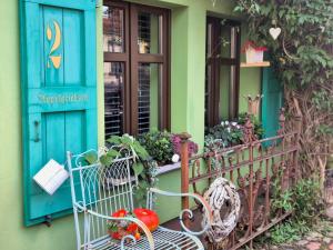 a porch with a blue door and a bench with fruits and vegetables at Appelgriebsch in Neukalen