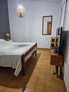 een slaapkamer met een bed, een spiegel en een televisie bij Espacio ideal in Mar de Ajó