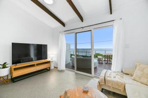 un soggiorno con divano e TV e un balcone di The Breakers a Sunderland Bay