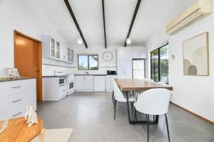 una cucina con mobili bianchi, tavolo e sedie di The Breakers a Sunderland Bay