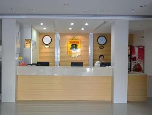 Super 8 Hotel Jinan Railway Station Square في جينان: امرأة تجلس على طاولة في مطعم مع الساعات