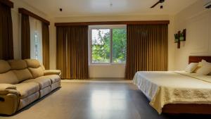 Mizuki Homestay في تريشور: غرفة نوم بها سرير وأريكة ونافذة