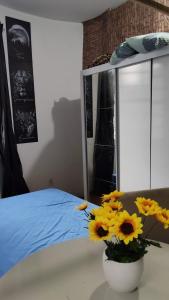 un vaso con fiori gialli su un tavolo accanto a un letto di Pernoite para rapazes apartamento compartilhado a San Paolo