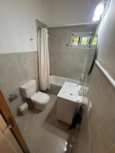 a bathroom with a white toilet and a sink at Cedro Azul in La Cumbre +19 photos