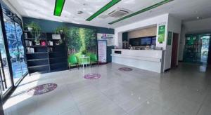 a lobby with a counter and green chairs in a building at Vatica JiangsuJianguo Road Xuanwu Market Hotel in Xuzhou