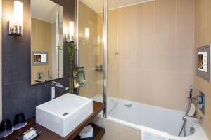 a bathroom with a white sink and a bath tub at Hôtel Barrière Le Gray d'Albion in Cannes