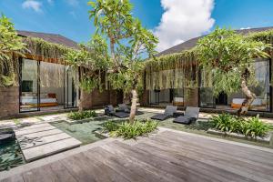 Un patio con sillas y árboles frente a un edificio. en Kalapa and Merica Luxury Villas Ubud, en Gianyar