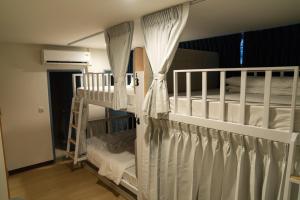 two bunk beds with white curtains in a room at Greet Hostel & Cafe Samyan in Bangkok