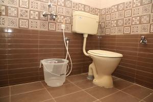 a bathroom with a toilet and a trash can at Sudha Grand Guestinn in Nellore +41 photos
