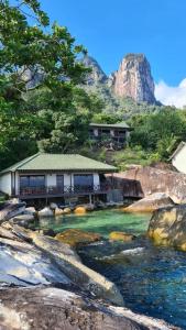 a house on a river with a mountain in the background at Minang Cove Resort in Tioman Island