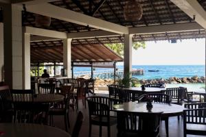 a restaurant with tables and chairs and a view of the ocean at Minang Cove Resort in Tioman Island