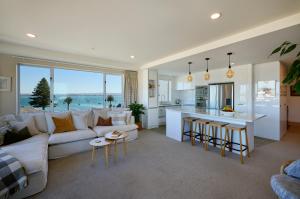 a living room with a white couch and a kitchen at Beaumont Apartments in Mount Maunganui