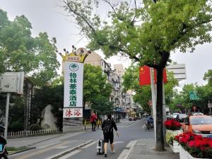 GreenTree Inn Express Shanghai Baoshan District Youyi Road Metro Station في Baoshan: شخص يركب لوح تزلج على شارع مع لافته