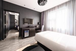 een slaapkamer met een bed, een bureau en een televisie bij Orange Hotel Hangzhou Wenyi West Road in Hangzhou