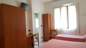 a bedroom with two beds and a cabinet and a window at Hotel Fortuna in San Bartolomeo al Mare