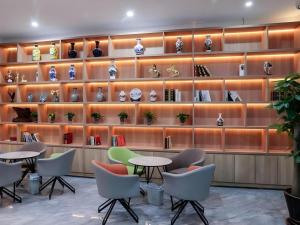 GreenTree Inn Express Shandong Qingdao Chengyang District Aodong Road في تشينغداو: غرفة بها طاولات وكراسي ورفوف مع مزهريات