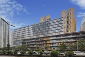 Gya Hotel Chengdu Global Center Jinchenghu Metro Station في تشنغدو: مبنى كبير مع سيارات متوقفة أمامه