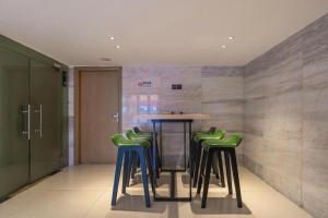 City Comfort Inn Foshan Shunde Daliang Qinghui Garden Food City في شوند: غرفة بها طاولة وأربعة مقاعد خضراء