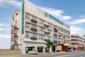 City Comfort Inn Zhanjiang Central People's Hospital High-speed Railway Station في Tchia-k'am: مبنى أبيض كبير مع سيارة متوقفة أمامه