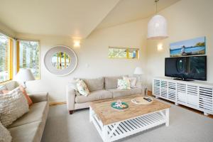 a living room with a couch and a tv at Island View - Stay Waiheke in Palm Beach