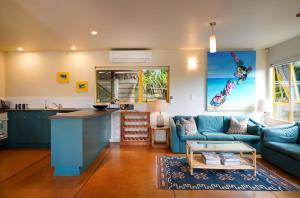 a kitchen and living room with a blue couch at Island View - Stay Waiheke in Palm Beach