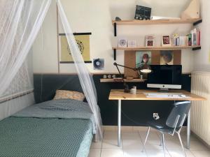 een slaapkamer met een bed en een bureau met een computer bij Chez Corinne in Valence