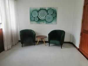 Una habitación con dos sillas y una mesa y un cuadro. en Villa NU 380, en Galle