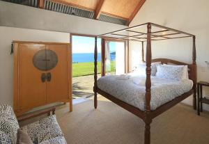 a bedroom with a canopy bed and a large window at The Pah - Stay Waiheke in Onetangi