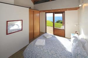 a bedroom with a bed and a sliding glass door at The Pah - Stay Waiheke in Onetangi