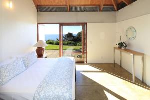 a bedroom with a bed and a view of the ocean at The Pah - Stay Waiheke in Onetangi