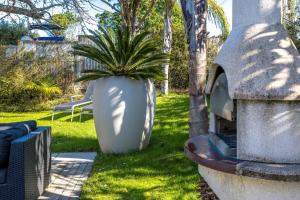 a large white pot with a plant in a yard at Welcome Cottage - Stay Waiheke in Oneroa