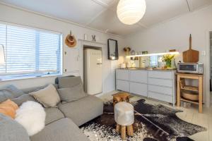 a living room with a couch and a kitchen at Welcome Cottage - Stay Waiheke in Oneroa