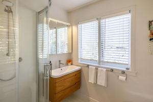 a bathroom with a sink and a shower and a window at Welcome Cottage - Stay Waiheke in Oneroa +14 photos
