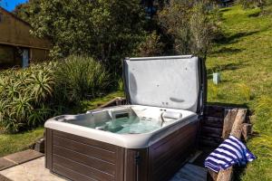 The Vineyard Cottage - Stay Waiheke في Onetangi: حوض استحمام ساخن في الفناء الخلفي مع