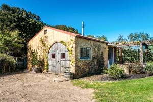 The Vineyard Cottage - Stay Waiheke في Onetangi: حظيرة قديمة مع باب في الفناء