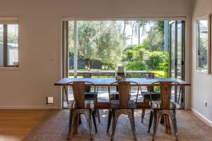 Un comedor con mesa y sillas y una gran ventana. en Paradise on Palm - Stay Waiheke, en Palm Beach