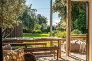 un patio con un banco de madera y una mesa en Paradise on Palm - Stay Waiheke, en Palm Beach
