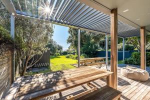 un patio al aire libre con un banco de madera y una mesa en Paradise on Palm - Stay Waiheke, en Palm Beach