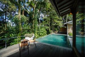 una piscina en una terraza con 2 sillas y una mesa en Sacred Jewel by GenuineHost, en Payangan