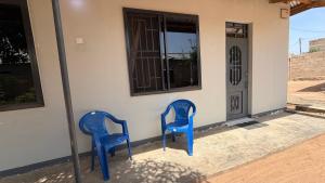 two blue chairs sitting outside of a house at COMFORT HAVEN Studio in Ilemera