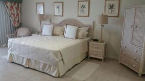 um quarto com uma grande cama branca e uma cadeira em Coral Sands Beach Resort em Bridgetown